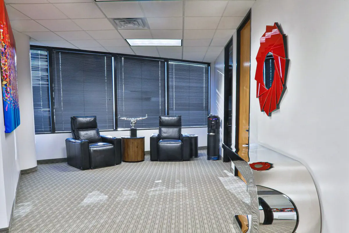 A room with two black chairs and a red mirror.