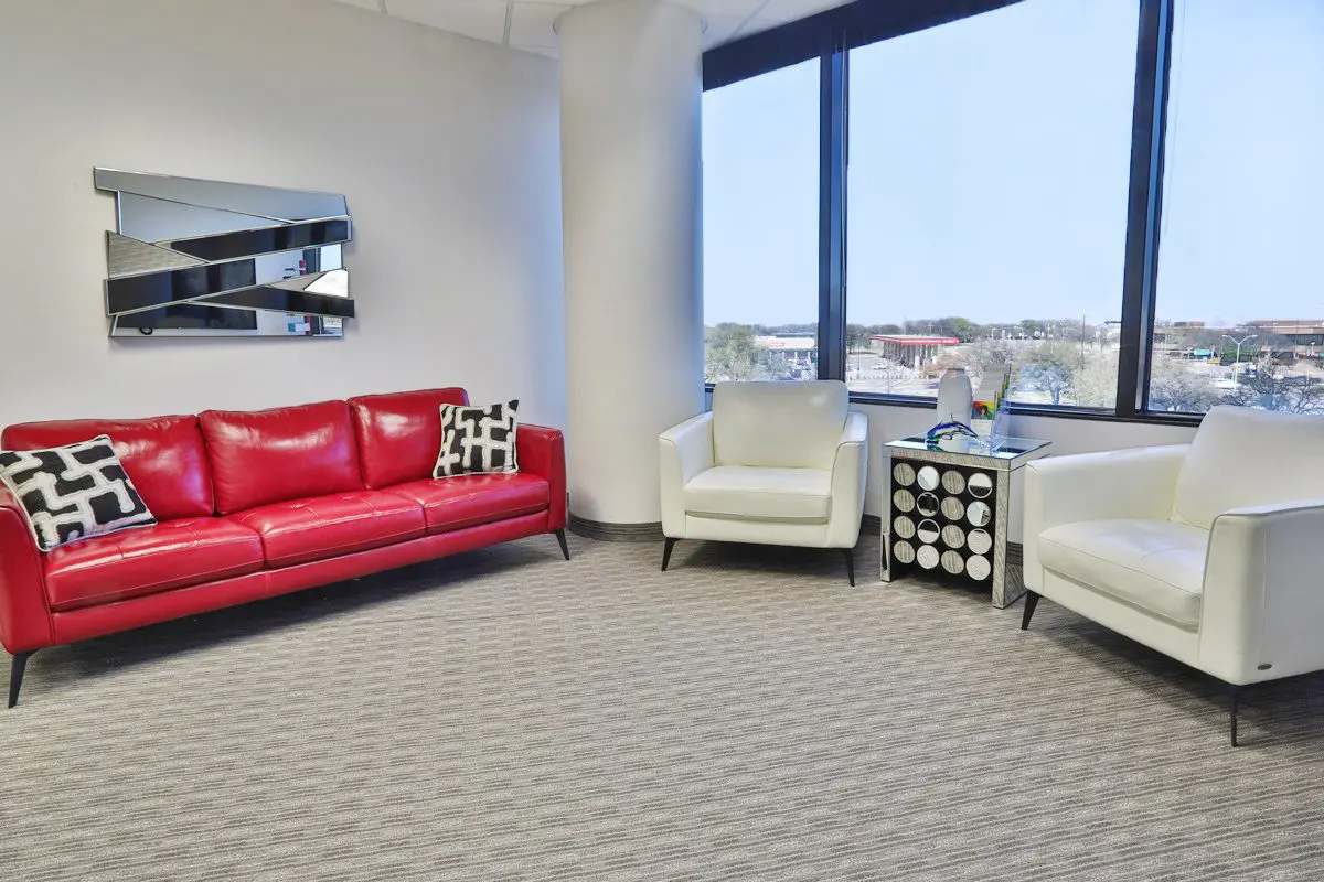 A living room with two chairs and a red couch