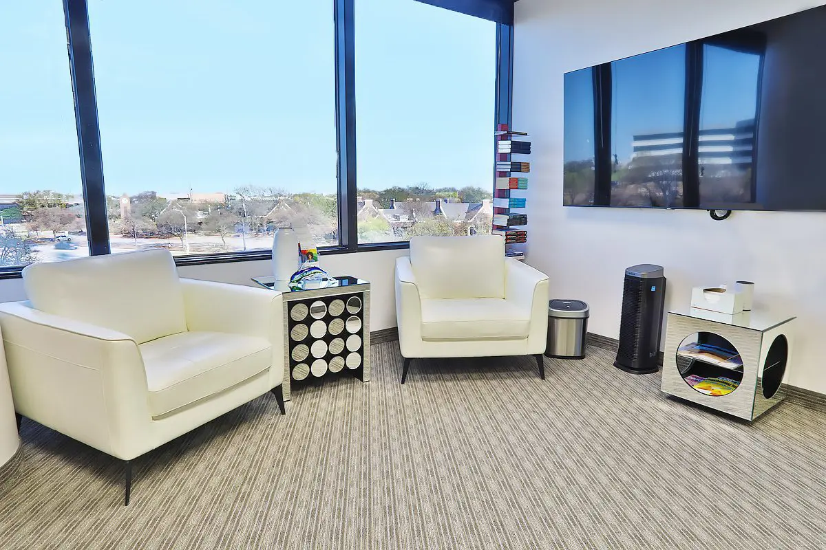 A room with two white chairs and a television.